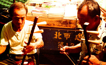 二胡のような南方の楽器を合奏する売人と友人